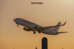 Boeing 737 de Flybondi matrícula LV-KDQ despegando con el tren de aterrizaje aún desplegado, con luz de atardecer y la silueta de un edificio alto de fondo