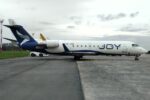 Bombardier CRJ200 LV-JOI de Joy Airline con librea azul y blanca estacionado en plataforma, con titulado JOY en el fuselaje y un tractor de remolque en el tren de nariz