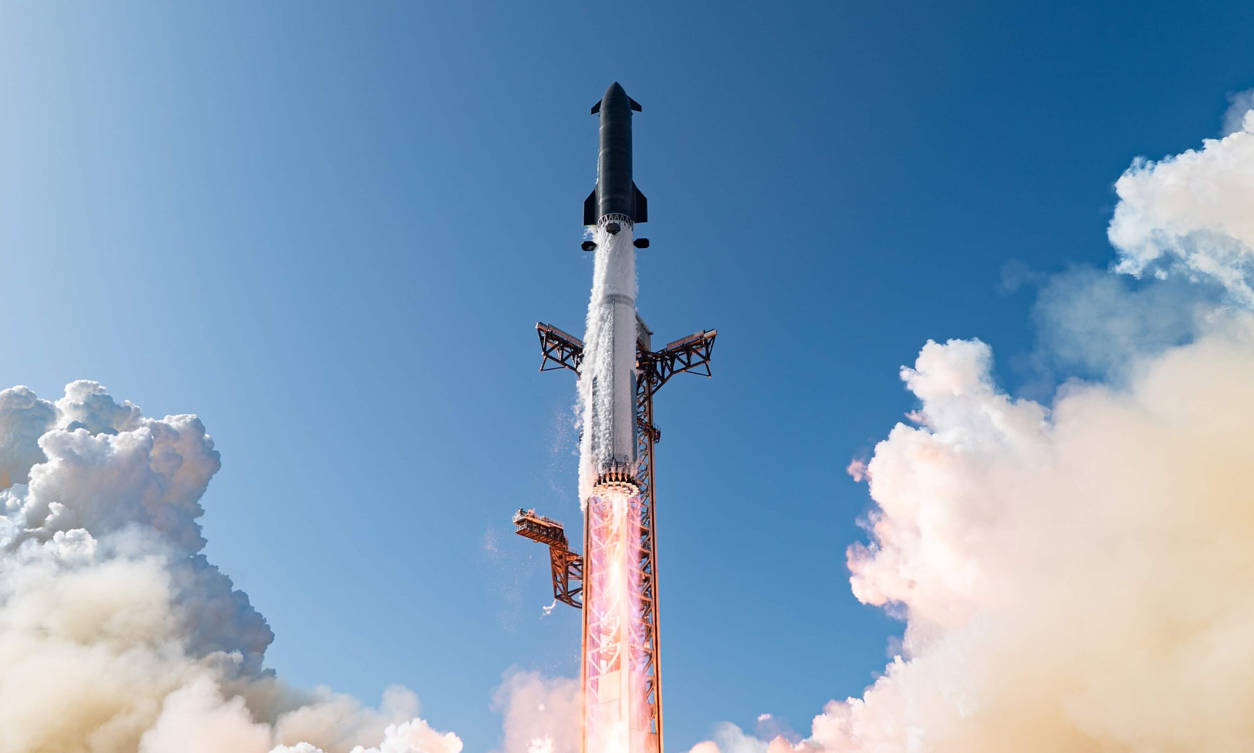 Cohete Starship de SpaceX despegando desde la torre de lanzamiento, con llamas y vapor en la base y cielo azul con nubes